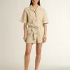 Damen-Jumpsuit aus beigem Denim mit Gürtel und ausgefranstem Saum Damen-Jumpsuit aus beigem Denim mit Gürtel und ausgefranstem Saum