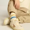 Getragene weiße Kindersocken mit Used-Details und zweifarbigen Streifen in leuchtendem Blau und Senfgelb