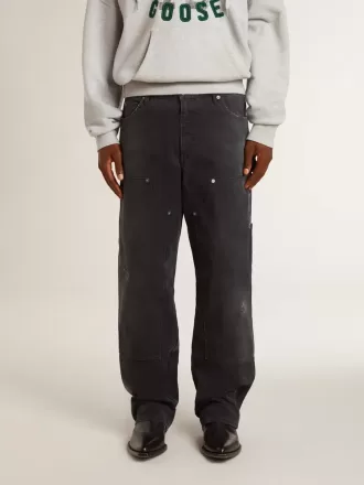 Herrenjeans aus schwarzem Baumwollstoff im Distressed-Look mit Aufnähern auf der Vorderseite