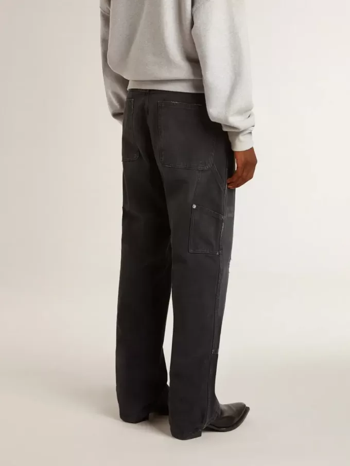 Herrenjeans aus schwarzem Baumwollstoff im Distressed-Look mit Aufnähern auf der Vorderseite