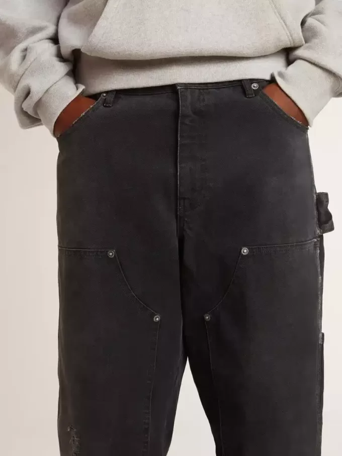 Herrenjeans aus schwarzem Baumwollstoff im Distressed-Look mit Aufnähern auf der Vorderseite