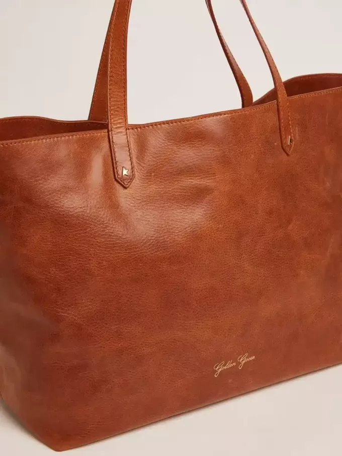 Pasadena-Tasche aus hellbraunem, glänzendem, gehämmertem Leder mit goldenem Logo auf der Vorderseite