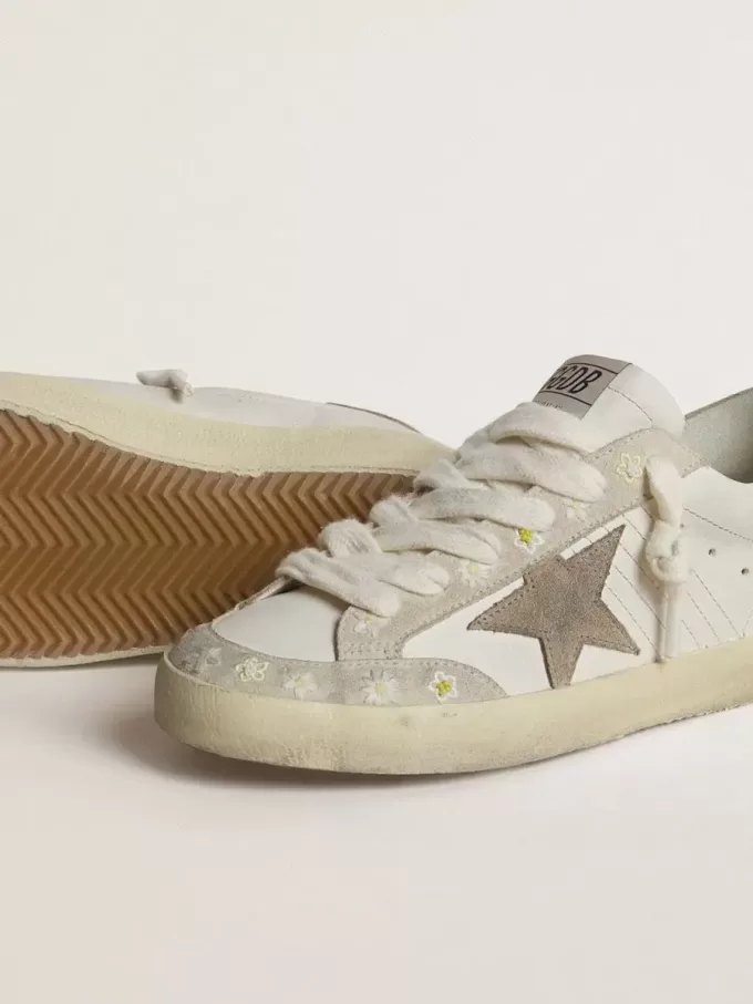 Super-Star LTD für Damen mit beigem Wildlederstern und Fersenlasche sowie Blumenstickerei Super-Star LTD für Damen mit beigem Wildlederstern und Fersenlasche sowie Blumenstickerei